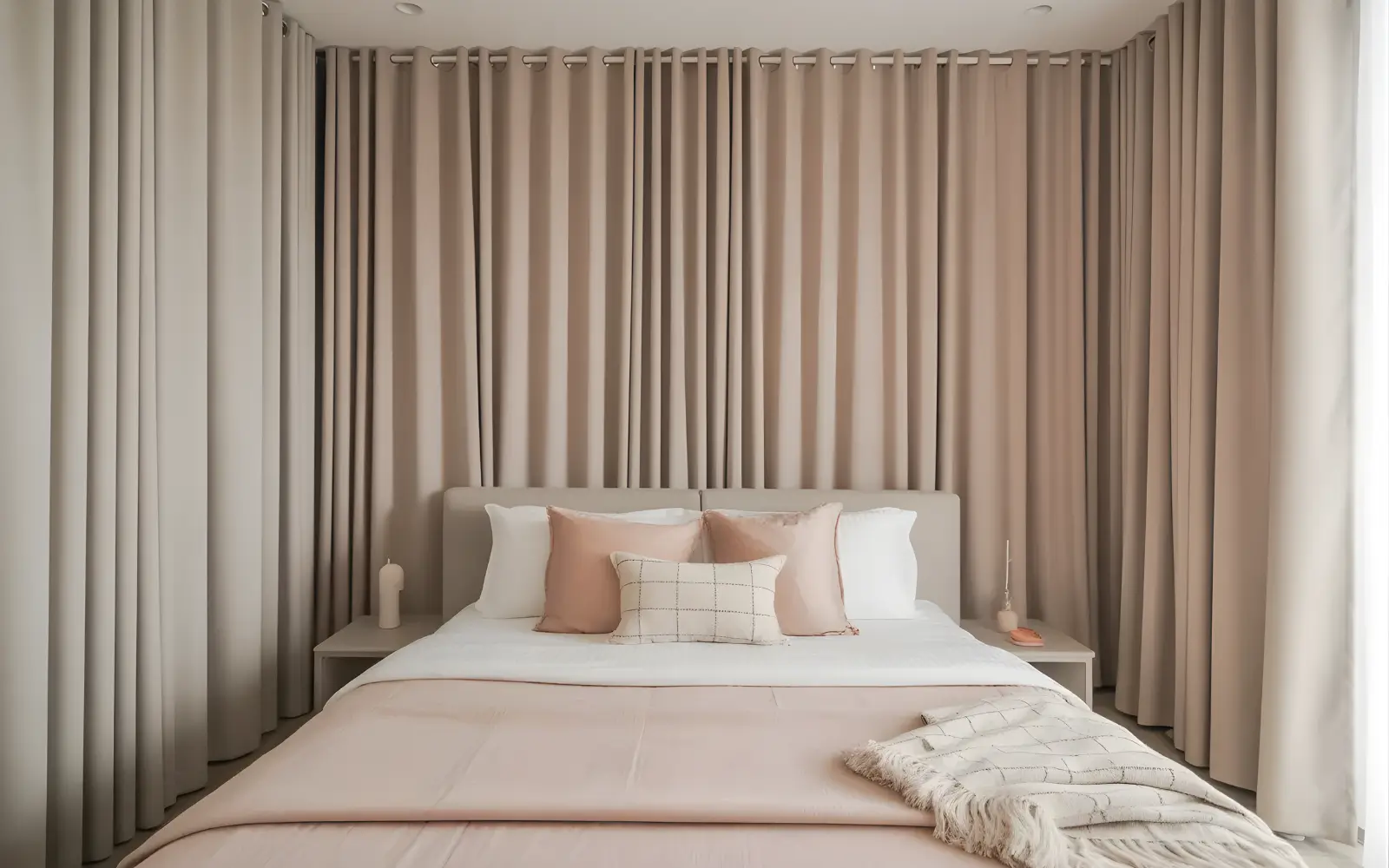 Small studio apartment where a full wall of curtains sits behind the bed, softly zoning the sleeping area from the rest of the space.