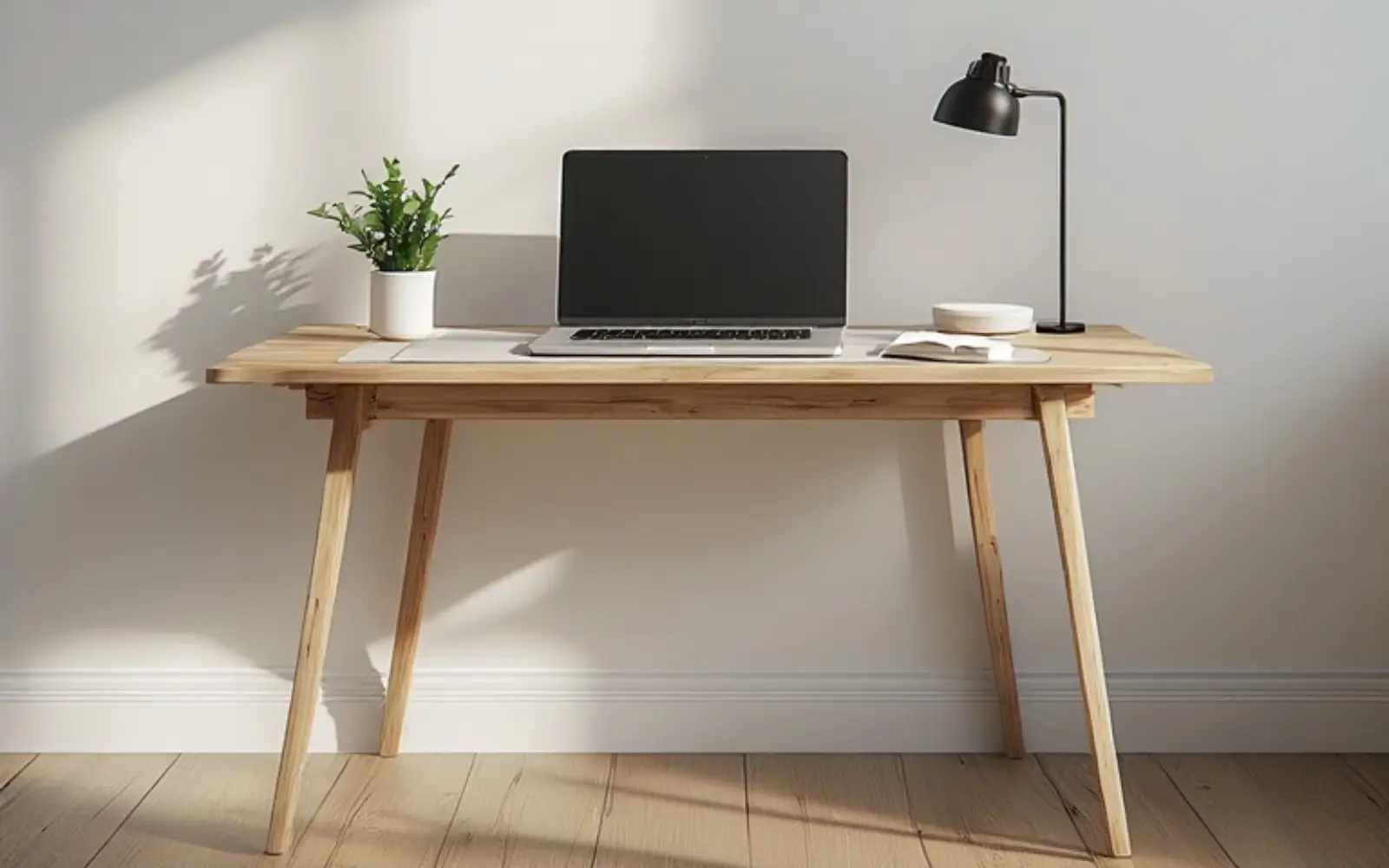 Compact light oak desk against a soft white wall in a small apartment, styled minimally for a feminine home office.