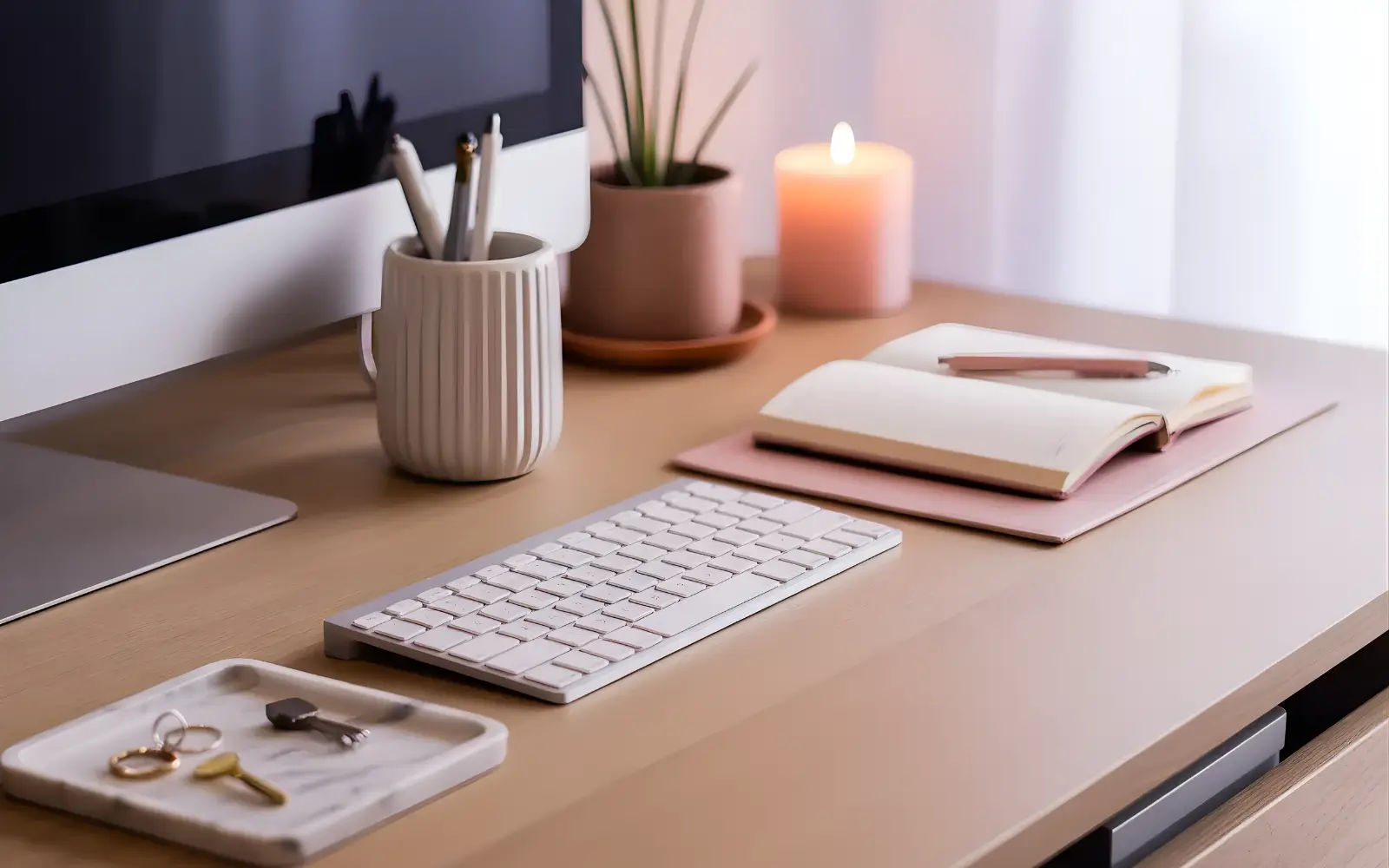 Close-up of a curated feminine desk surface with a few essential tools and decor pieces.