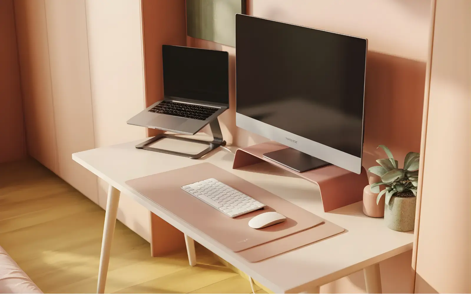 Narrow white desk with a slim monitor and laptop on a stand, styled in a feminine palette.