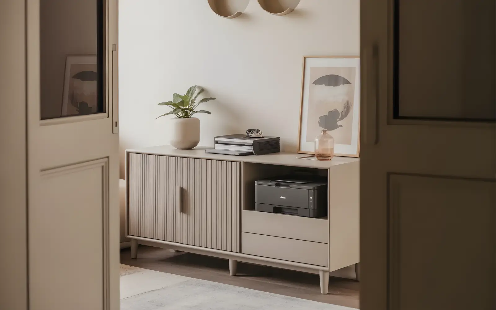 Styled home office sideboard with closed doors, a small plant on top and all cables hidden, in a feminine small apartment.
